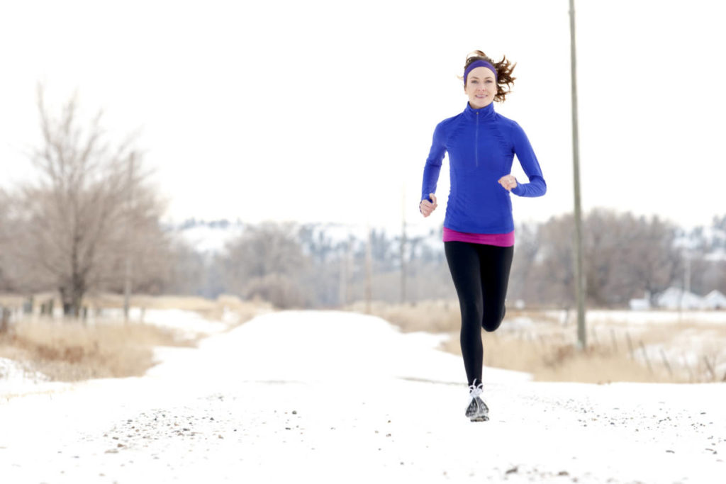 An Athletic woman jogging in the winter.
